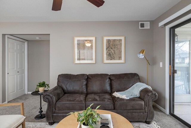 living room with light colored carpet, a textured ceiling, and ceiling fan