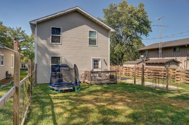 rear view of house featuring a trampoline, a yard, and a deck