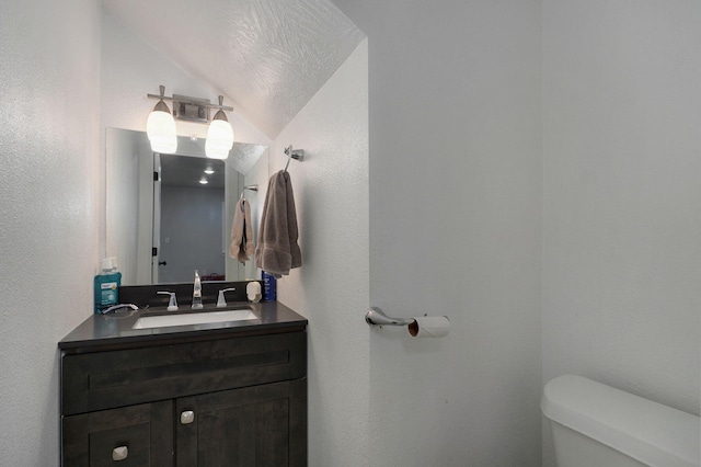 bathroom with vaulted ceiling, vanity, and toilet