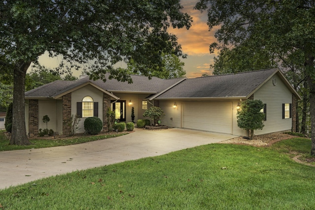 ranch-style house featuring a garage and a yard