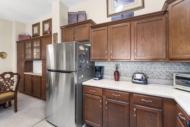 kitchen with backsplash, stainless steel refrigerator, and light colored carpet