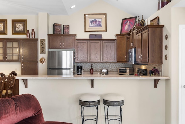 kitchen with appliances with stainless steel finishes, a kitchen bar, and vaulted ceiling