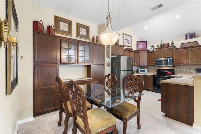 dining area with lofted ceiling, sink, and light colored carpet