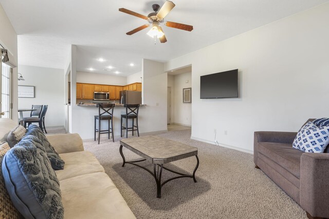 living room with light carpet, baseboards, and ceiling fan