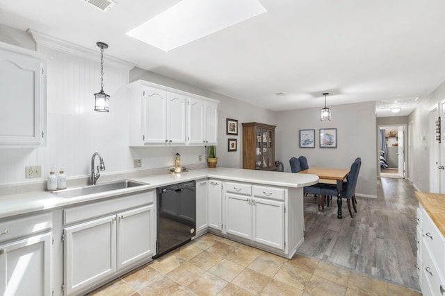 kitchen featuring kitchen peninsula, dishwasher, white cabinets, and decorative light fixtures