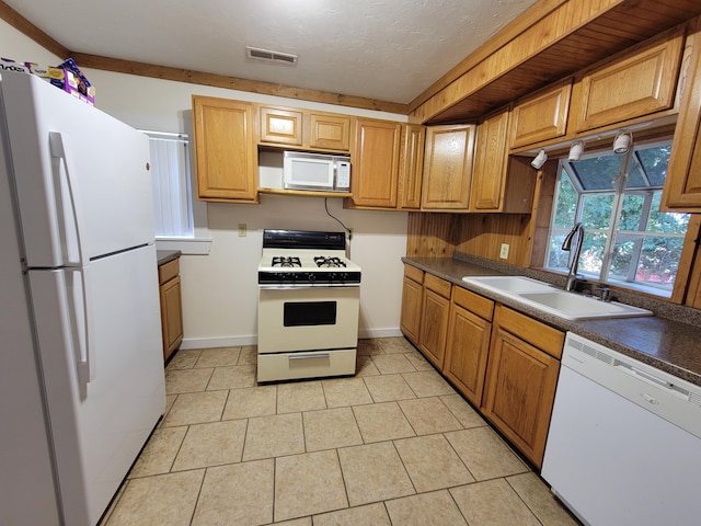 kitchen featuring dark countertops, a sink, white appliances, and light tile patterned floors
