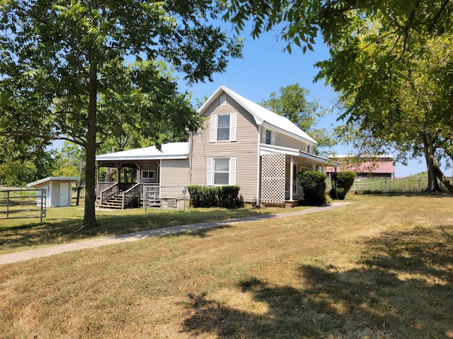 traditional-style home featuring fence, a porch, a front lawn, and metal roof