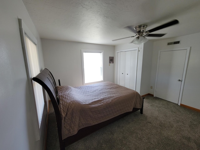 bedroom featuring ceiling fan, a closet, dark carpet, and a textured ceiling