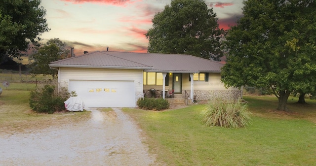 single story home with a yard, covered porch, and a garage