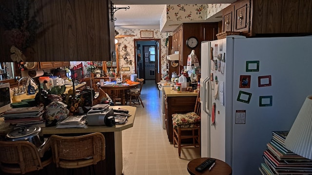 kitchen featuring dark brown cabinetry, white refrigerator, and a textured ceiling