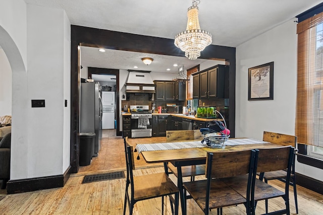 dining space featuring a textured ceiling, light hardwood / wood-style flooring, a chandelier, and sink