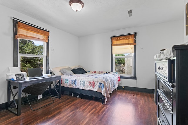 bedroom with a textured ceiling, multiple windows, and dark hardwood / wood-style flooring