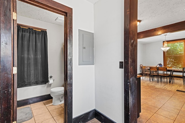 bathroom featuring electric panel, toilet, a textured ceiling, and tile patterned floors