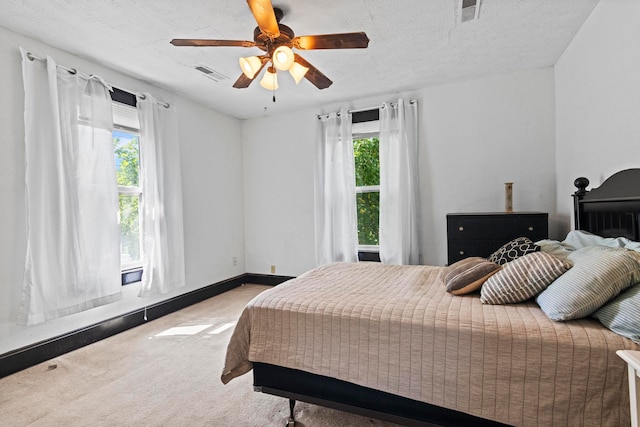 bedroom featuring multiple windows, ceiling fan, carpet floors, and a textured ceiling