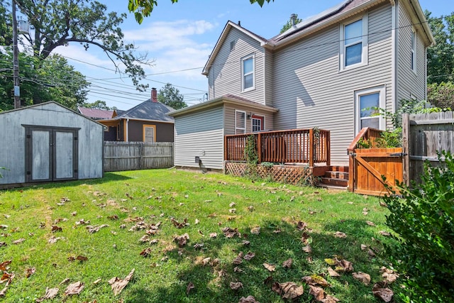 rear view of house with a wooden deck, a shed, and a lawn