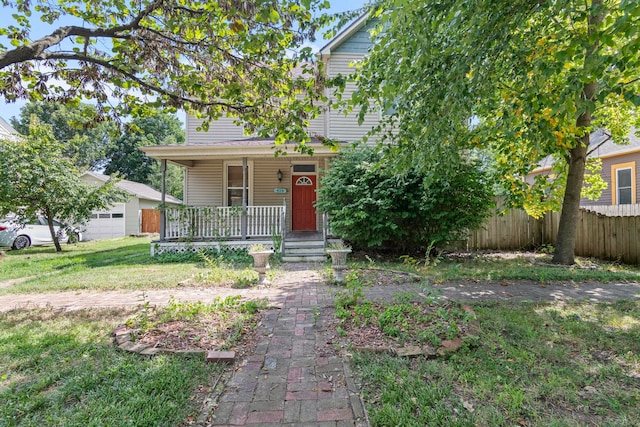 view of front of property featuring a front yard, a garage, and covered porch