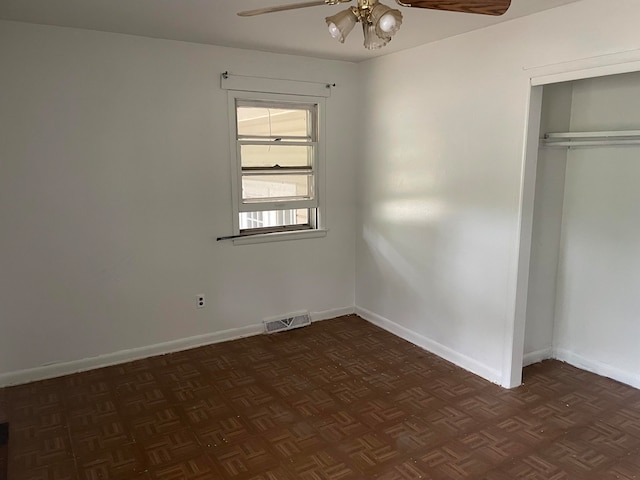 unfurnished bedroom with dark parquet floors, ceiling fan, and a closet