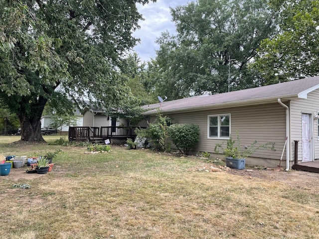 back of property featuring a wooden deck and a yard