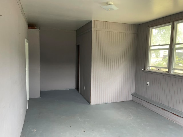 unfurnished room with wood walls and concrete flooring