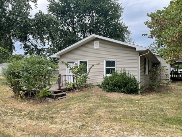 rear view of property featuring a wooden deck and a lawn