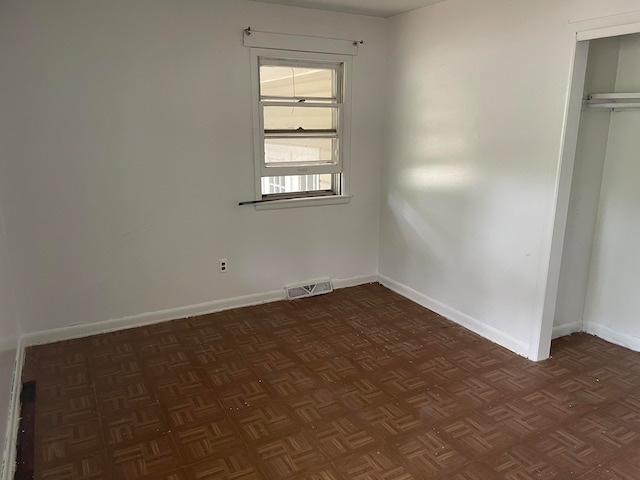 unfurnished bedroom with dark parquet flooring