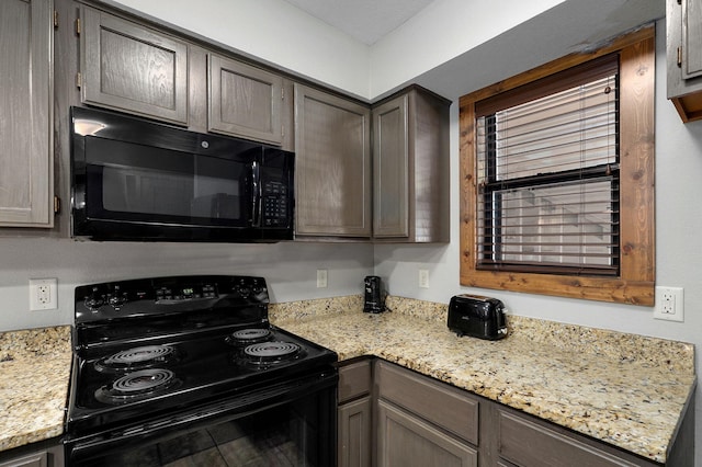 kitchen with light stone counters, black appliances, and plenty of natural light