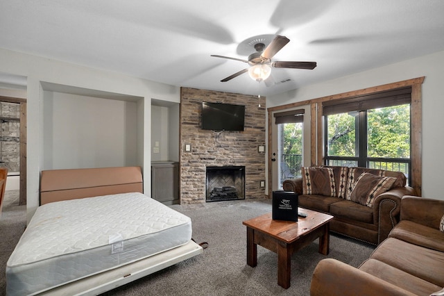 living room with ceiling fan, a stone fireplace, and carpet flooring