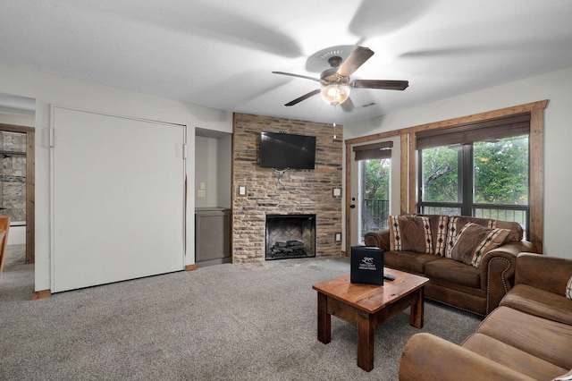 living room featuring ceiling fan, carpet floors, and a stone fireplace