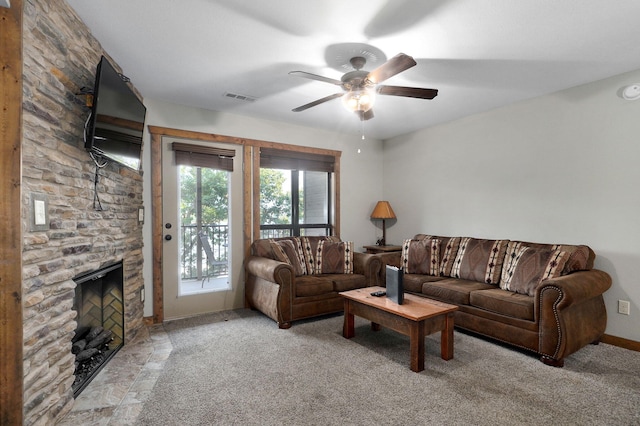 carpeted living room with ceiling fan and a fireplace