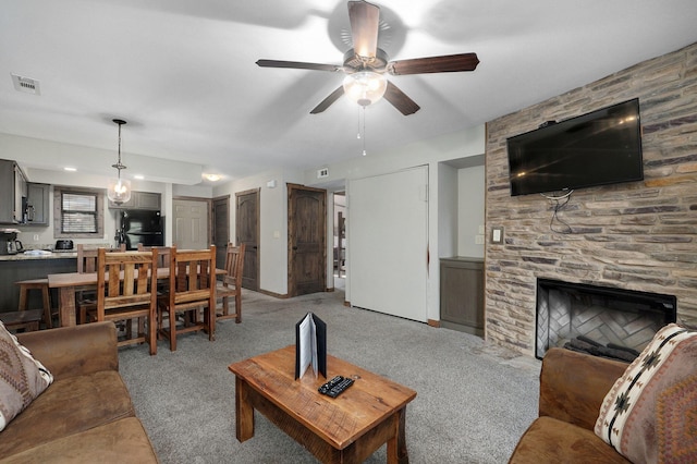 carpeted living room with a fireplace and ceiling fan