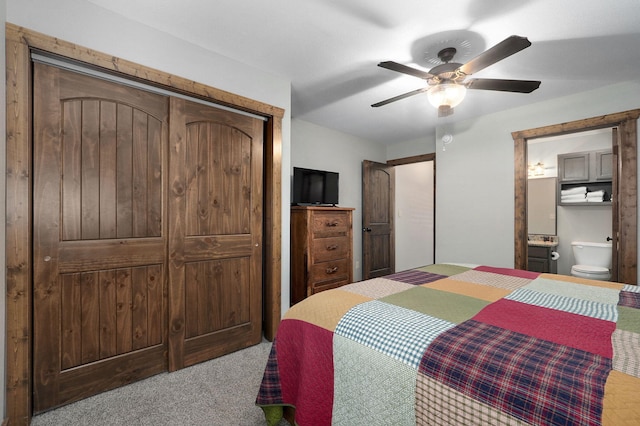 bedroom with a closet, light carpet, ensuite bath, and ceiling fan