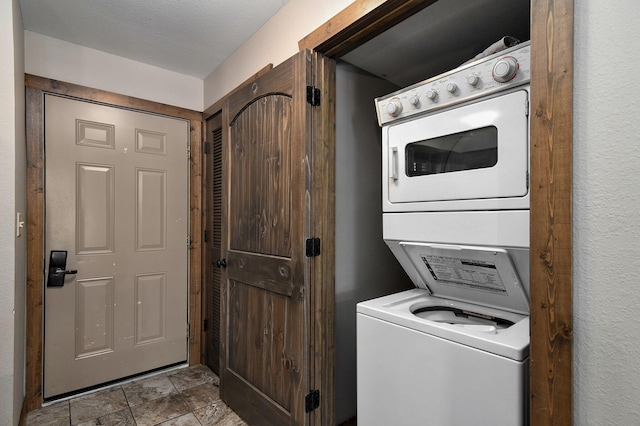 laundry area with stacked washer and clothes dryer and a textured ceiling