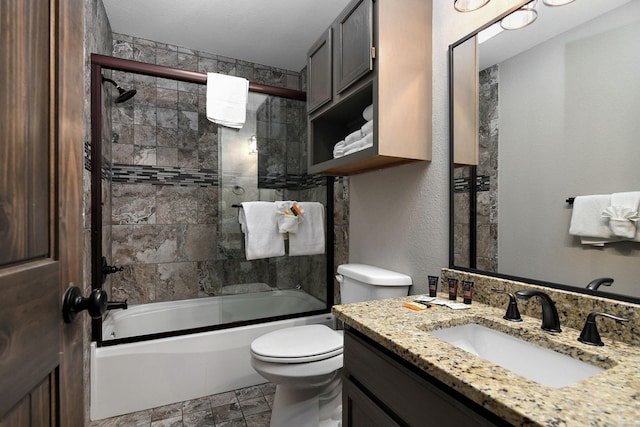 full bathroom with a textured ceiling, shower / bath combination with glass door, vanity, and toilet