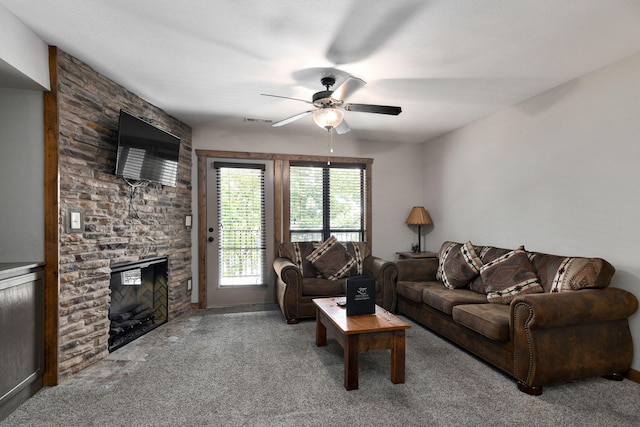 carpeted living room featuring ceiling fan and a stone fireplace