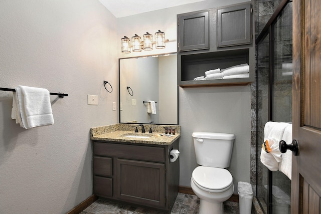 bathroom with a shower with shower door, vanity, and toilet