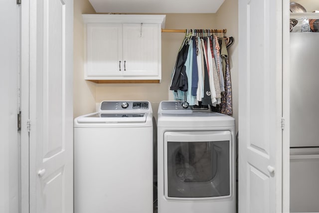 laundry room with washing machine and clothes dryer and cabinets