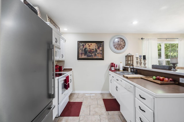 kitchen featuring white appliances, white cabinets, sink, and light tile patterned floors