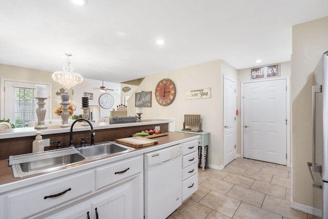 kitchen featuring ceiling fan with notable chandelier, sink, white dishwasher, hanging light fixtures, and white cabinetry