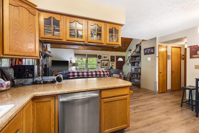 kitchen with vaulted ceiling, stainless steel dishwasher, light hardwood / wood-style floors, and a textured ceiling