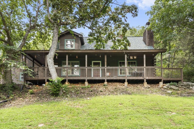 view of front of property featuring a shingled roof, log siding, a front yard, and a chimney