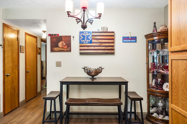 dining space featuring an inviting chandelier, light hardwood / wood-style floors, and a textured ceiling