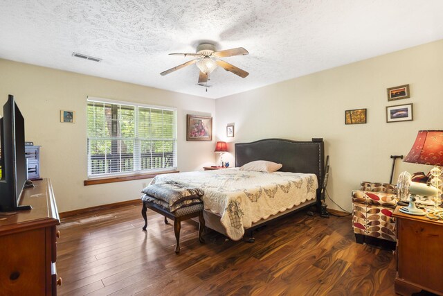 bedroom featuring ceiling fan, visible vents, a textured ceiling, and wood finished floors