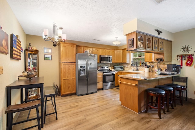 kitchen featuring sink, stainless steel appliances, light wood-type flooring, and kitchen peninsula