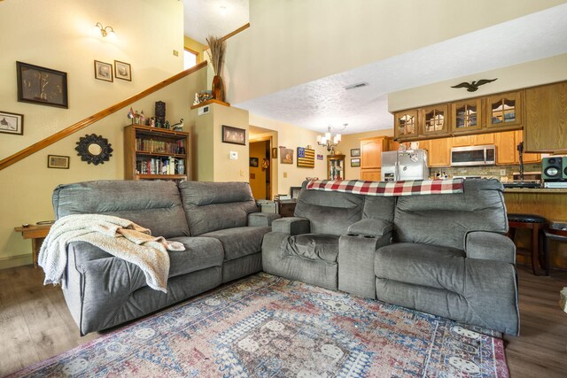 living area with a chandelier, wood finished floors, baseboards, and visible vents