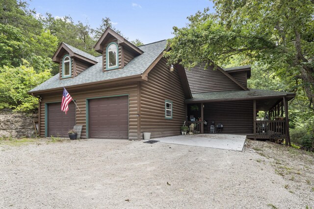 view of front of home featuring a garage, a shingled roof, driveway, and faux log siding