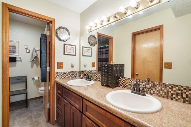 bathroom with vanity, tasteful backsplash, tile patterned flooring, toilet, and a textured ceiling