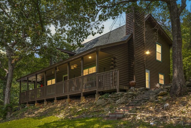 rear view of house with a chimney and a shingled roof