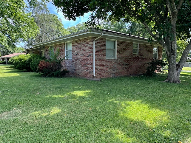 view of side of property with crawl space, a lawn, and brick siding