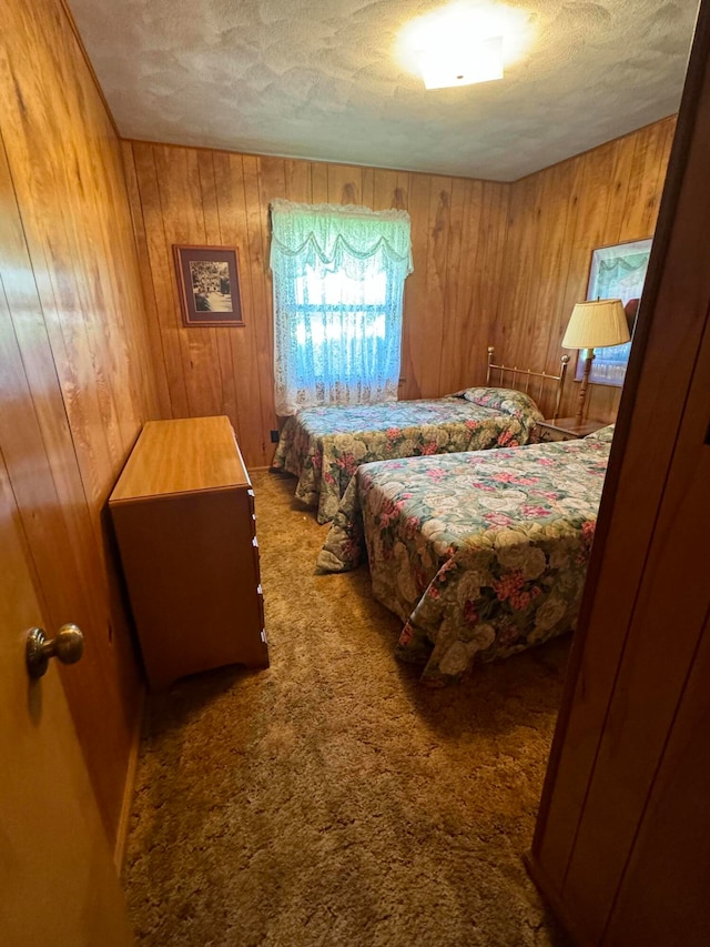 bedroom with carpet floors, a textured ceiling, and wooden walls