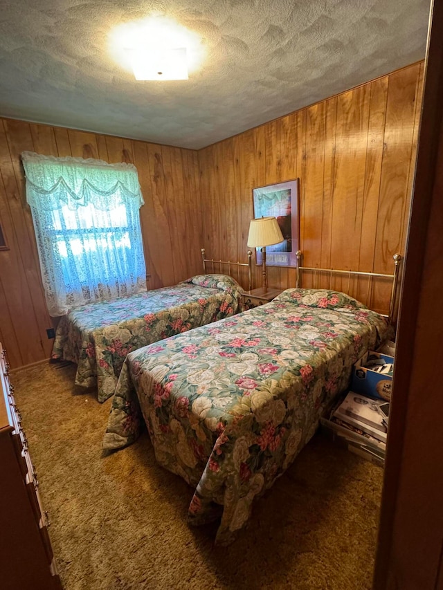 carpeted bedroom with wooden walls and a textured ceiling